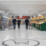 Supermarket yoʻlagidagi plitkada strelka va logotipli pol reklama stikeri