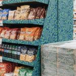 Supermarket yoʻlagida mahsulot qoʻyilgan brendlangan karton pol displeyi va palet displeyi